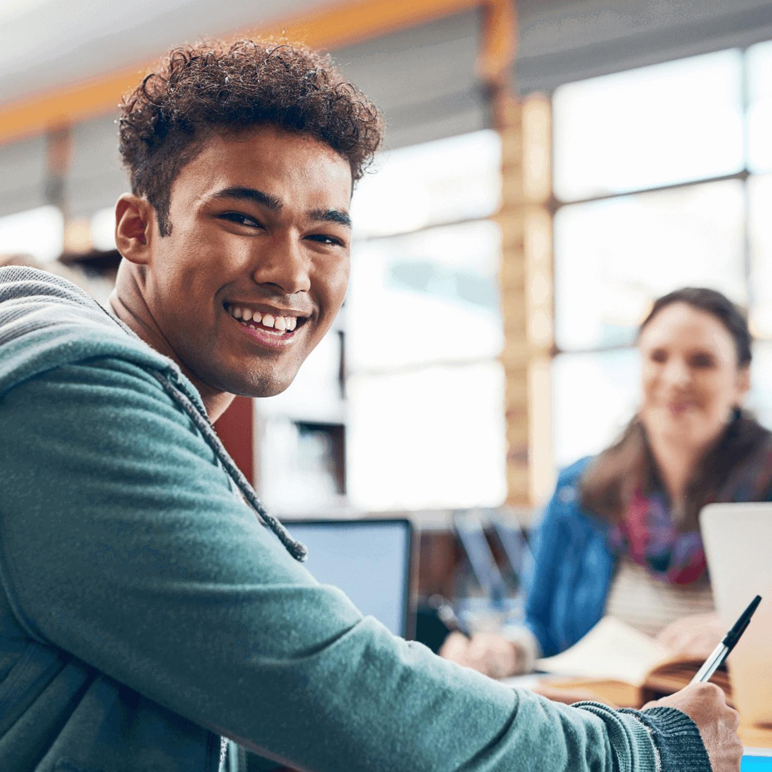 Smiling person sitting at a desk looking at the camera