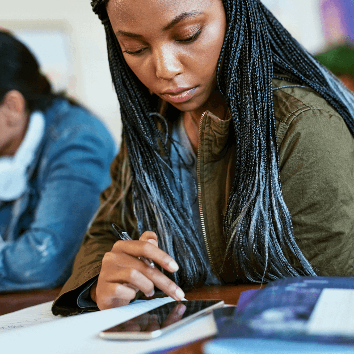 Person working at a table, looking at a phone